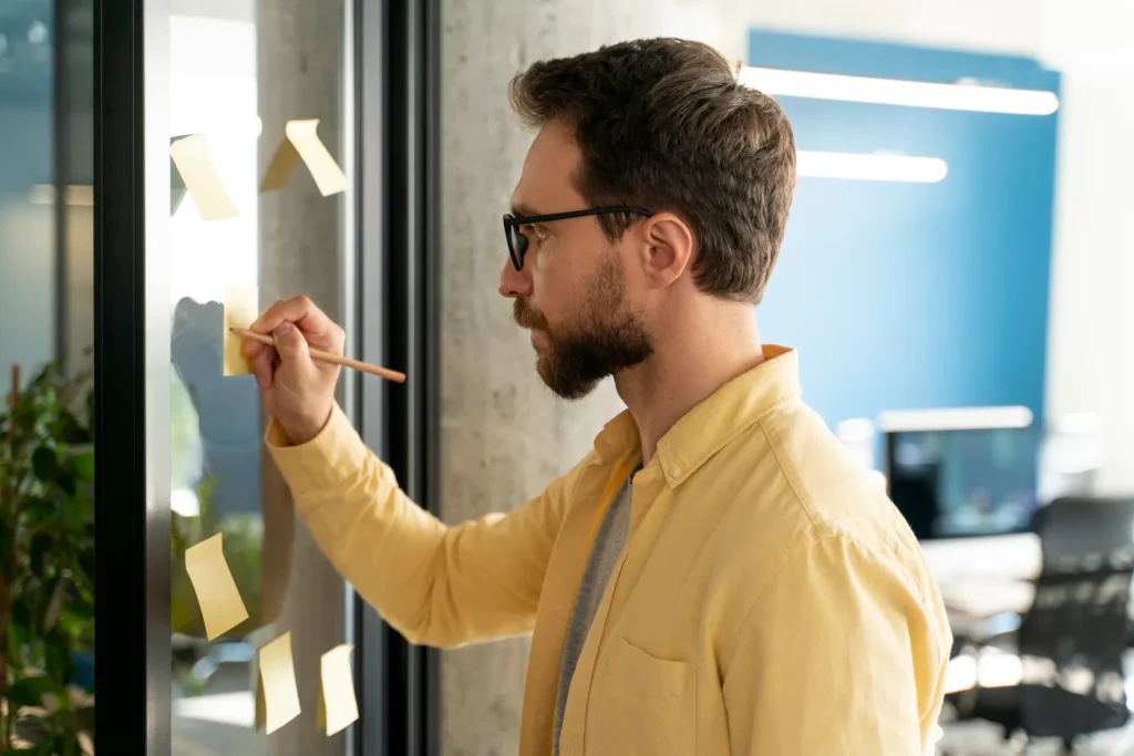 Product manager analyzing and organizing ideas on sticky notes while planning and evaluating AI-native product strategy, focusing on decision-making, risk, and building trustworthy AI systems.